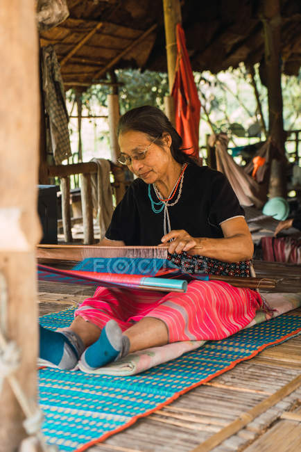 CHIANG RAI, THAILAND- 12 FEBBRAIO 2018: Donna asiatica anziana seduta a casa a lavorare lana . — Foto stock