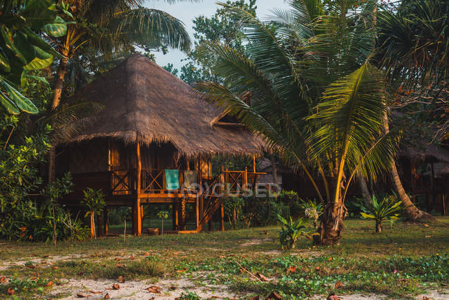 Small wooden house with straw roof at tropical lawn — Stock Photo