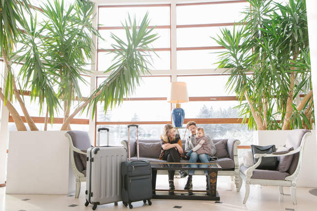 Cheerful family waiting on couch at lobby — Stock Photo