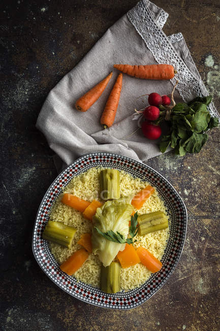 Vue juste au-dessus de la plaque avec couscous et légumes sur la table — Photo de stock