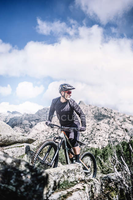 Biker maturo in sella alla bicicletta in montagna e guardando indietro — Foto stock