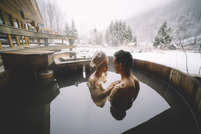 Sensual couple sitting in plunge tub in winter — Stock Photo