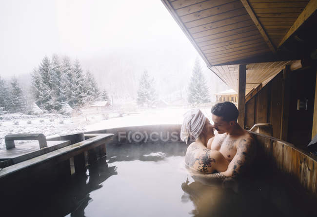 Couple assis en plein air plonger baignoire et baisers — Photo de stock