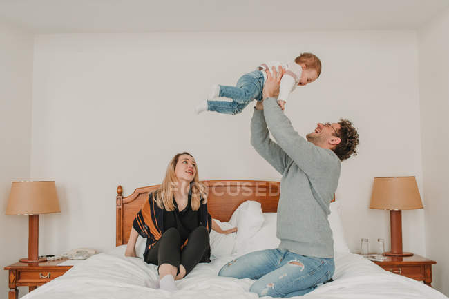 Familia jugando con el bebé en la cama en el hotel - foto de stock