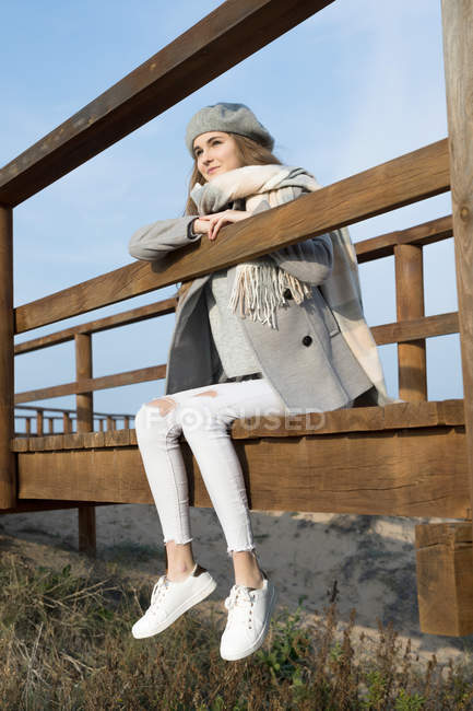 Verträumte Frau sitzt an sonnigem Tag auf der Strandpromenade — Stockfoto