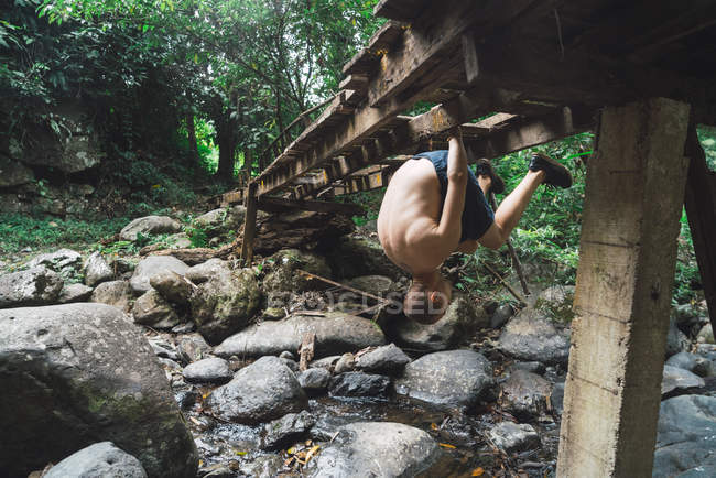 Man hanging upside down on old bridge — Stock Photo