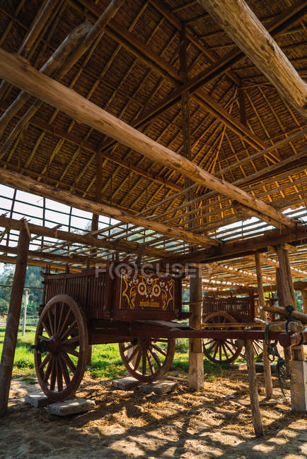 Big vintage wooden wagon parked under roof in village. — Stock Photo