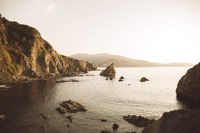 Tranquil view to cliffs and big rocks at seaside in evening. — Stock Photo