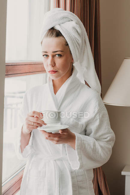 Задумчивая женщина пьет кофе после ванны — стоковое фото