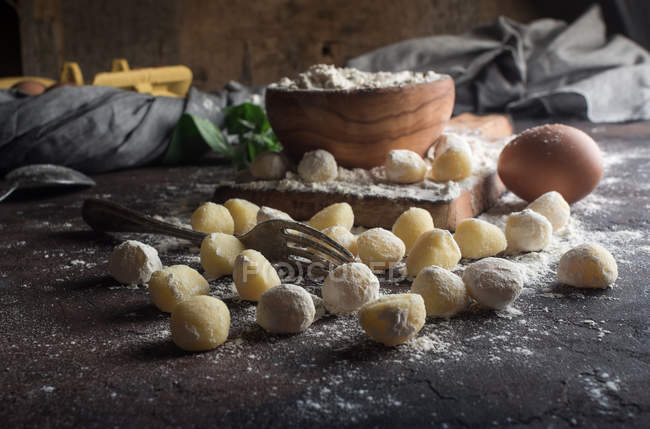 Rural ainda vida de nhoque cru e ingredientes na tábua de corte — Fotografia de Stock