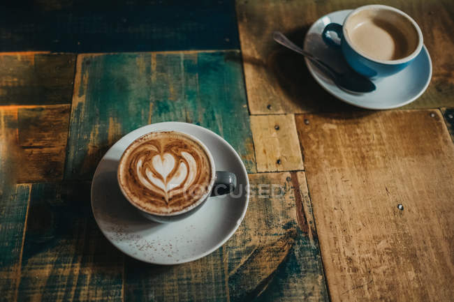 Copa de café con leche con flor en espuma de leche - foto de stock