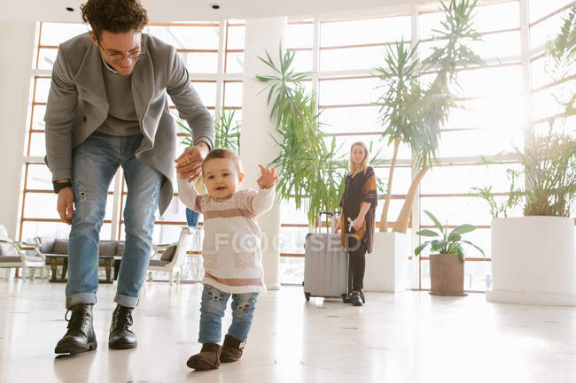 Famiglia con valigie nella hall dell'hotel illuminata dal sole — Foto stock