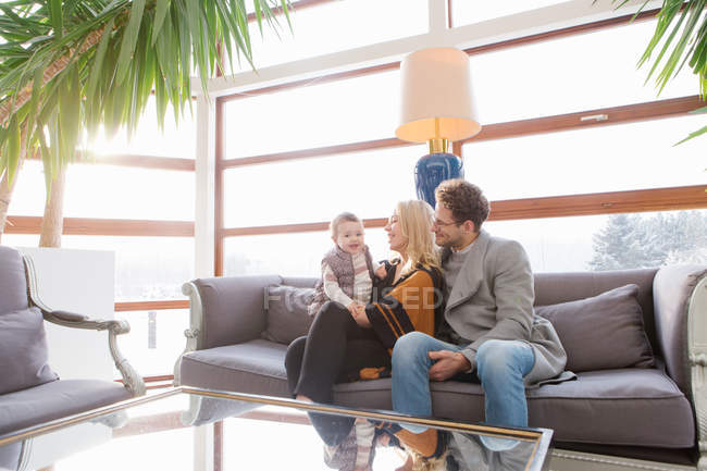 Cheerful parents with small son sitting on sofa in hotel hall. — Stock Photo