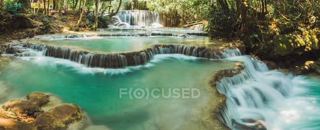 Panoramic view to small waterfalls flowing on sunny day — Stock Photo