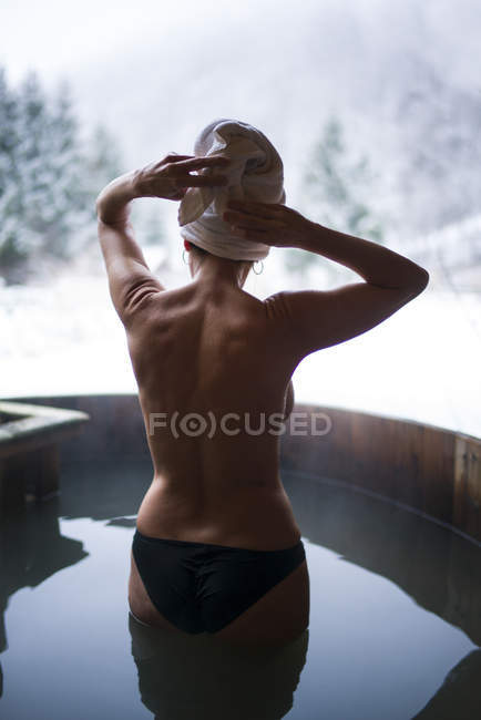 Rear view of topless woman posing n outside plunge tub in winter day. — Stock Photo