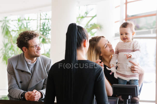 Jovem família se inscrevendo na recepção do hotel — Fotografia de Stock