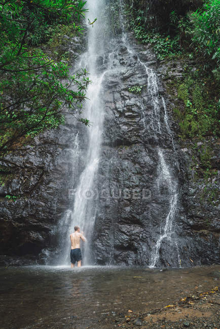 Vista posteriore di uomo che lava a cascata di cascata tropicale — Foto stock