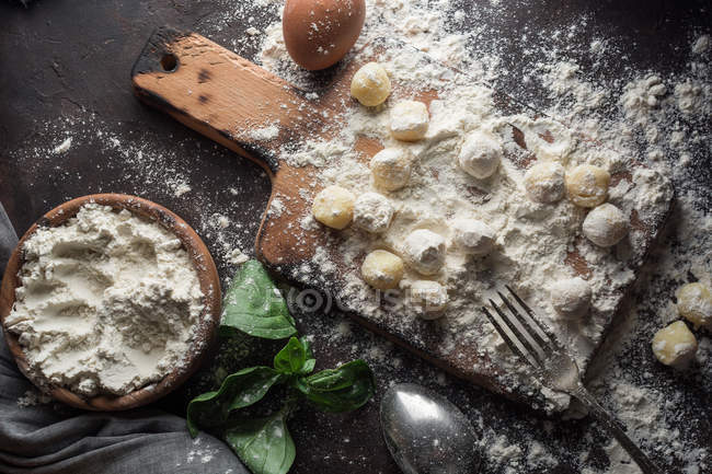 Directly above view of table with raw gnocchi on board and ingredients on table — Stock Photo