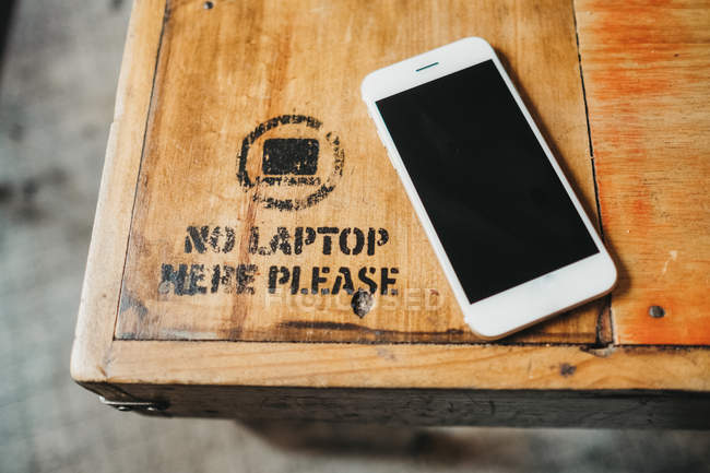 Зверху смартфон на дерев'яному столі зі знаком заборони ноутбука . — стокове фото