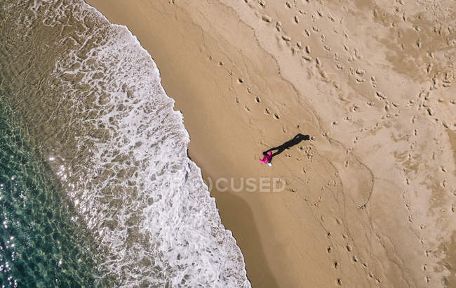 Directly above view of woman running on sand beach at sunny day. — Stock Photo