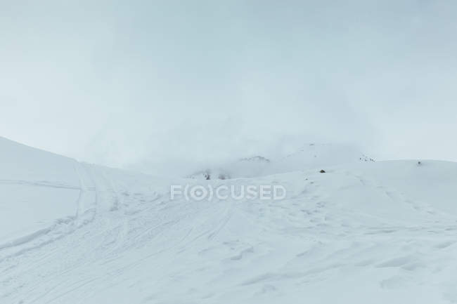 Снежный пейзаж туманной горы и неба — стоковое фото