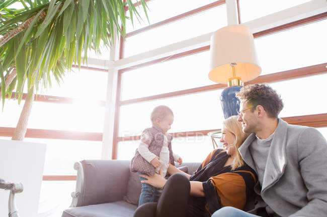 Allegro giovane famiglia con bambino sul divano in hotel — Foto stock