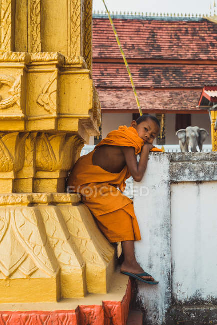 18. Februar 2018: Junger Mönch sitzt auf Zaun und blickt in Kamera — Stockfoto