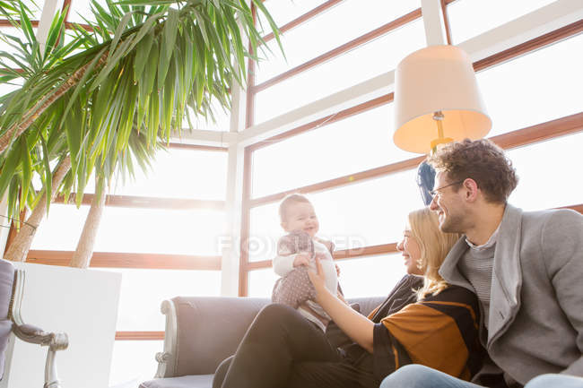 Fröhliche junge Familie mit Kind auf der Couch in der Hotellobby — Stockfoto