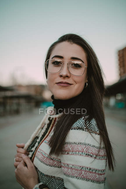 Young casual stylish woman looking at camera and standing on street. — Stock Photo