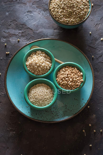 Direttamente sopra la vista di ciotole di ceramica piene di cereali e fiocchi di grano sul piatto . — Foto stock