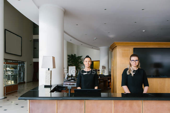 Two young women standing at hotel reception — Stock Photo