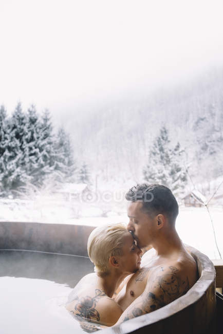 Sensual couple sitting in plunge tub in winter landscape — Stock Photo