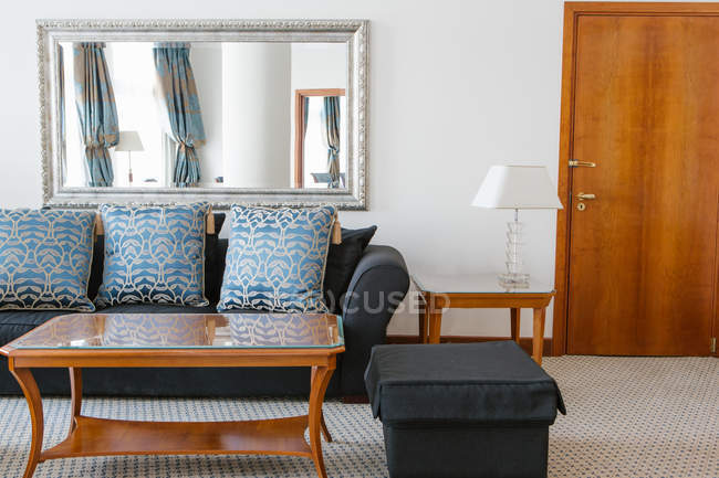 Interior of living room with blue sofa and mirror in apartment. — Stock Photo