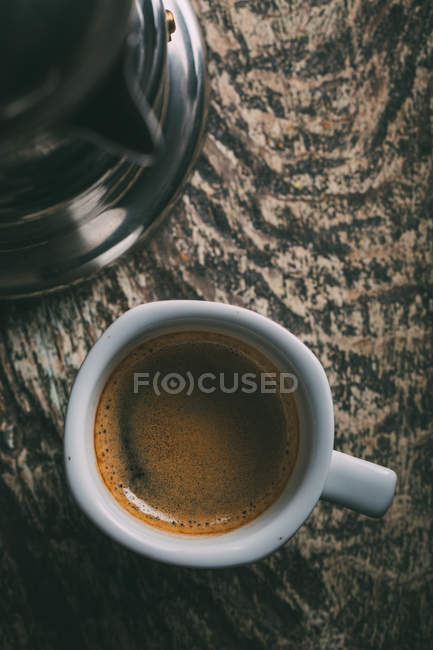Прямо над видом на чашку кофе на деревенском деревянном столе — стоковое фото