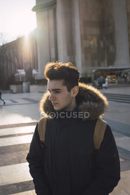 Nachdenkliche junge Touristen stehen im Sonnenlicht auf dem großen Platz und schauen zur Seite — Stockfoto