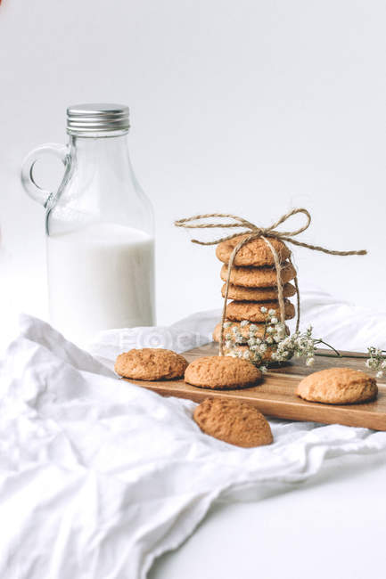 Glass bottle with milk and cookies on wooden table. — Stock Photo
