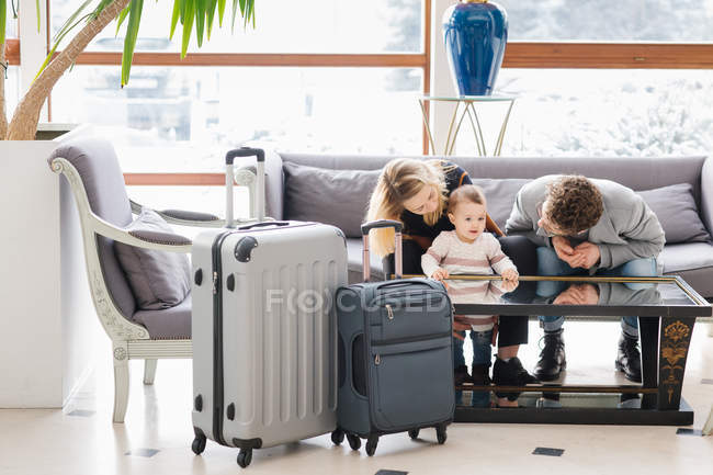 Alegre familia joven con niño en el sofá en el hotel - foto de stock