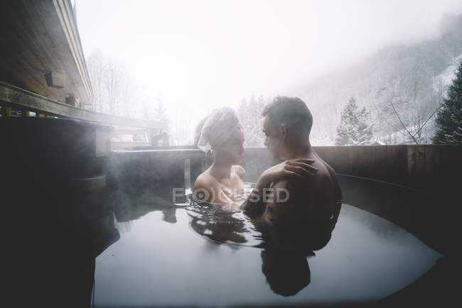 Pareja relajante en bañera de inmersión al aire libre en día de invierno - foto de stock