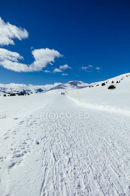Snow road on mountain slope under bright sky — Stock Photo