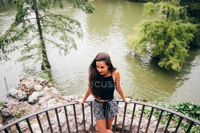 Brünette Frau lehnt am Geländer am Fluss. — Stockfoto