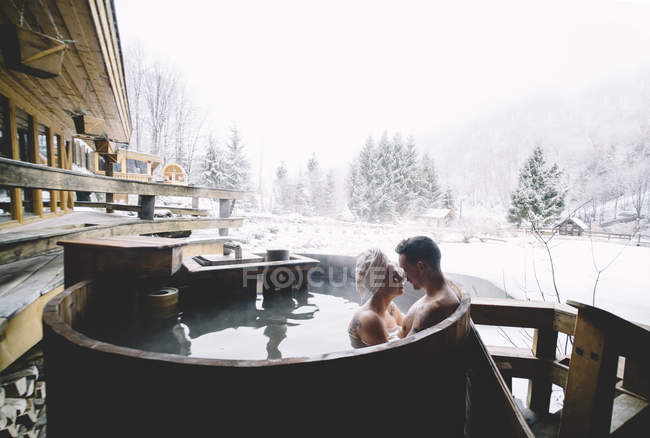 Couple embrasser dans la baignoire plongeante dans le paysage d'hiver — Photo de stock