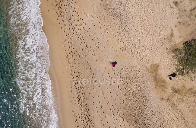 Вид с воздуха на женщину, бегущую по пустому пляжу в солнечный день . — стоковое фото
