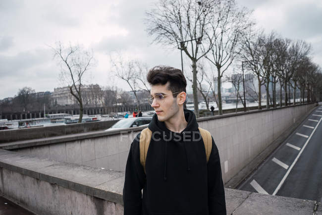 Надійний молодий турист в окулярах, що йде по вулиці і дивиться в сторону . — стокове фото