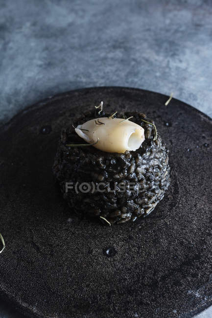 Close up view of black rice with cuttlefish on black cement dish — Stock Photo