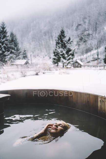 Blonde woman swimming in outdoor plunge tub at winter nature — Stock Photo