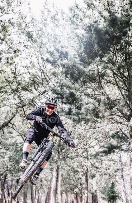 Mature cyclist jumps with mountain bike at nature — Stock Photo