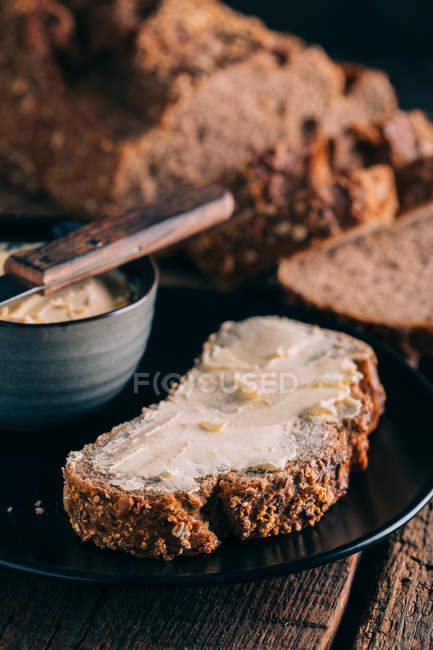 Slice of rustic bread with butter on plate — Stock Photo
