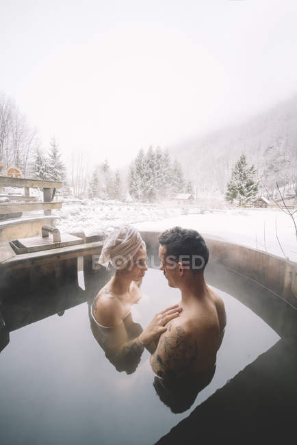 Romantic couple sitting in plunge tub in winter nature — Stock Photo