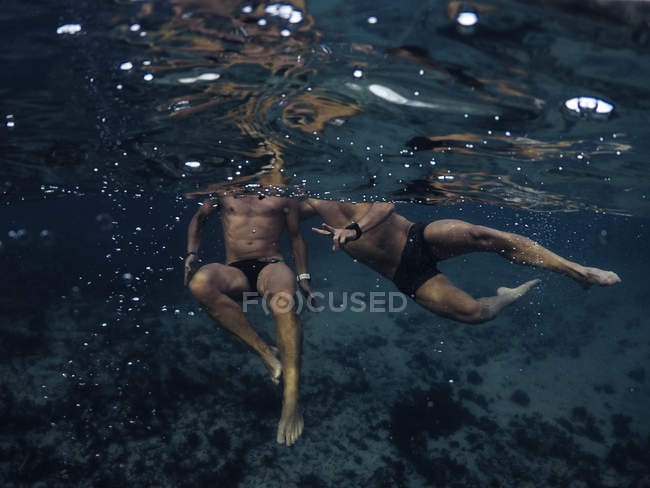 Vista submarina a los hombres nadando en el océano - foto de stock