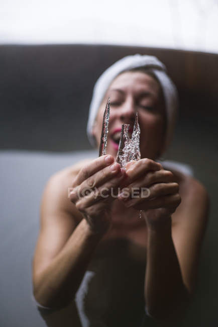 Cheerful woman in outside plunge tub showing icicle to camera. — Stock Photo